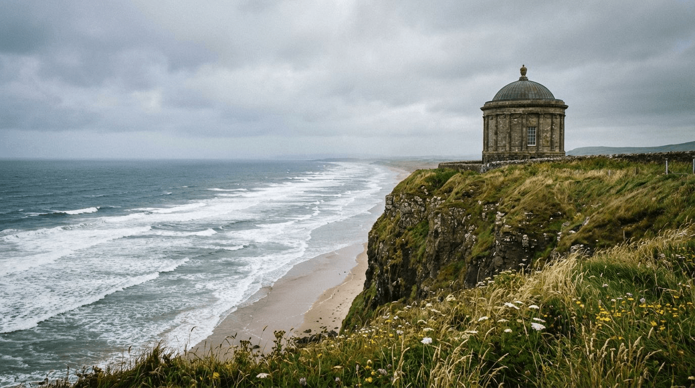 Mussenden Temple perched on dramatic cliff edge above Downhill Strand beach, waves crashing below, overcast sky