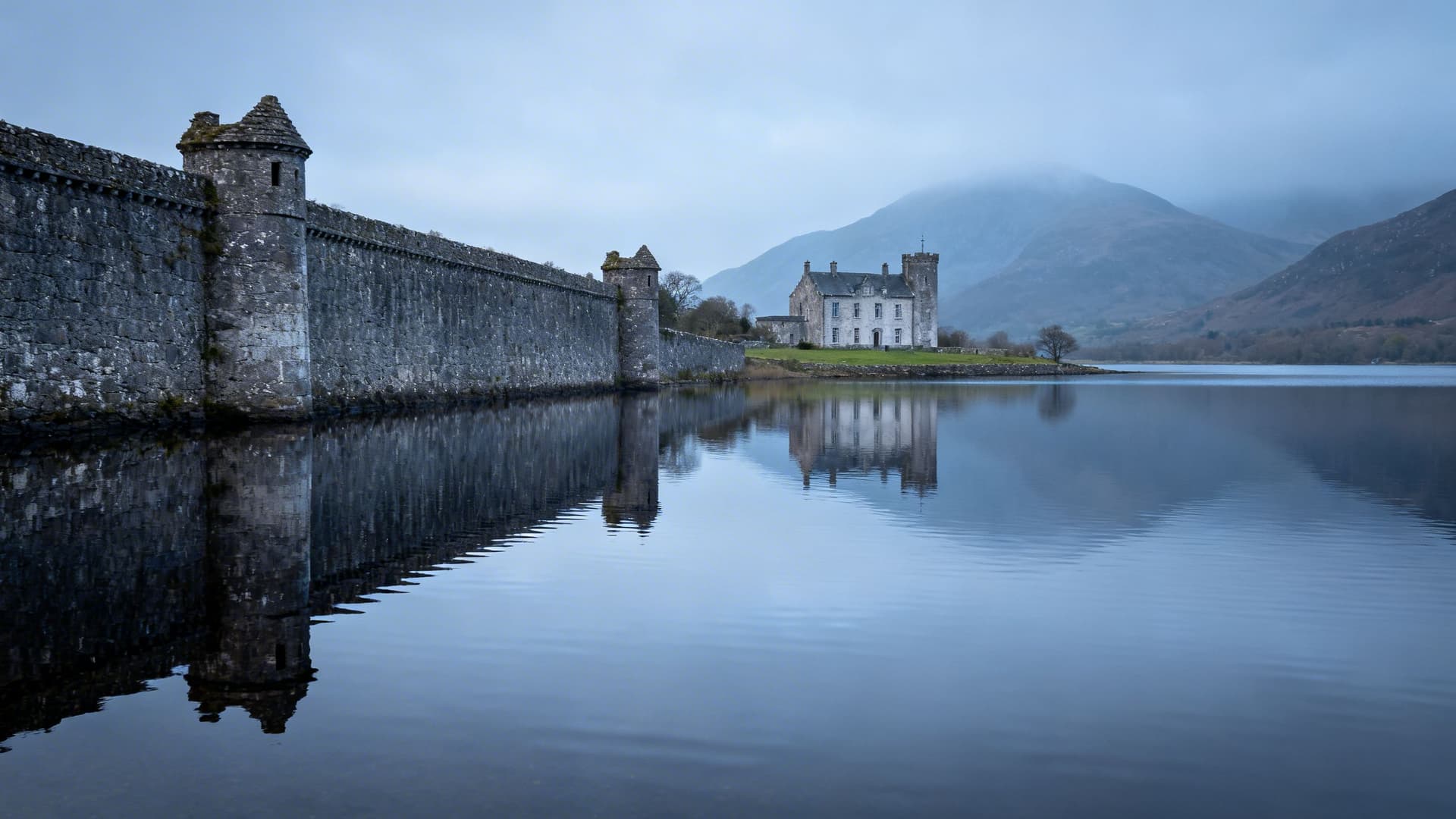Parke's Castle fortified manor house sitting on the shore of Lough Gill with its bawn wall and corner towers reflected in the still water