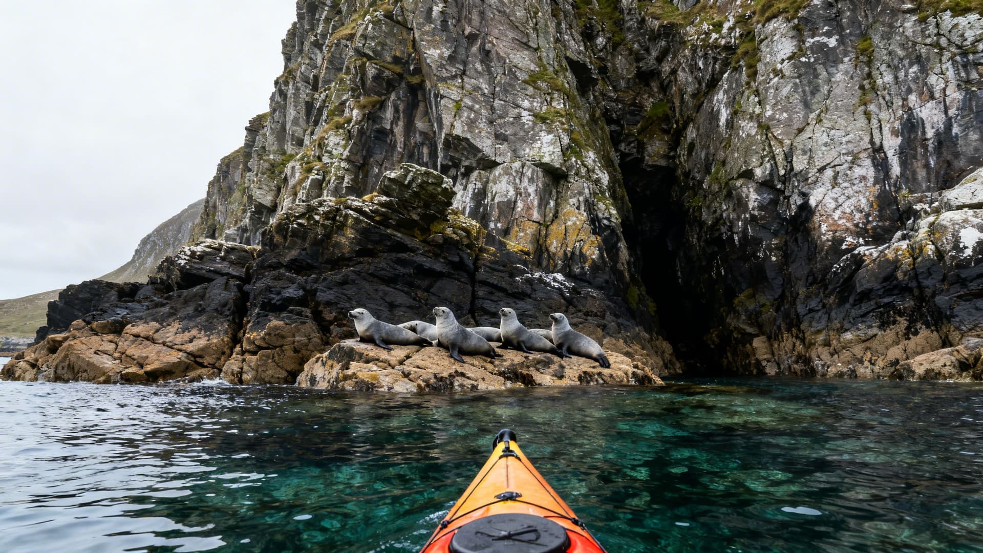 A sea kayaker paddling the Iveragh Peninsula coast at sea level, cliffs rising above from the water, Atlantic calm and clear