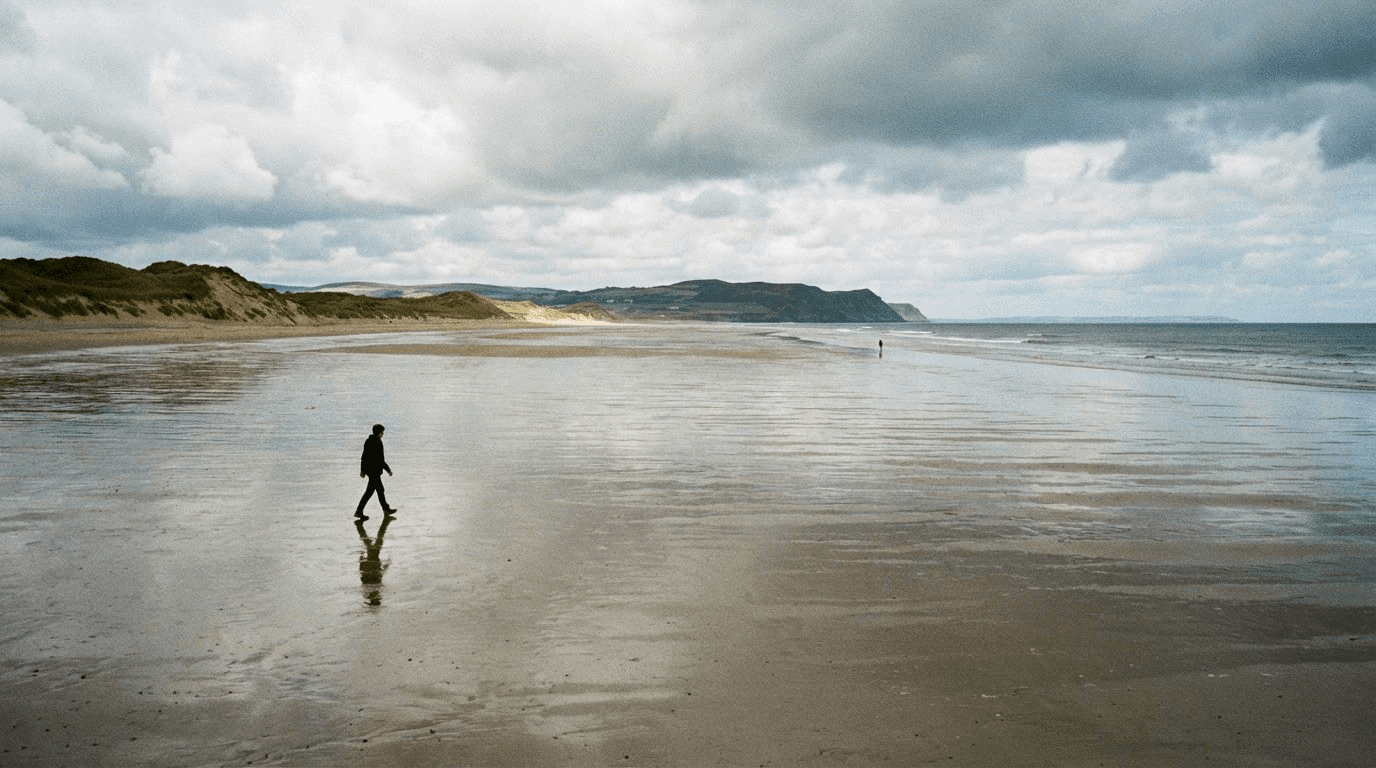 Person walking on Curracloe Beach at low tide with vast expanse of wet sand showing the scale