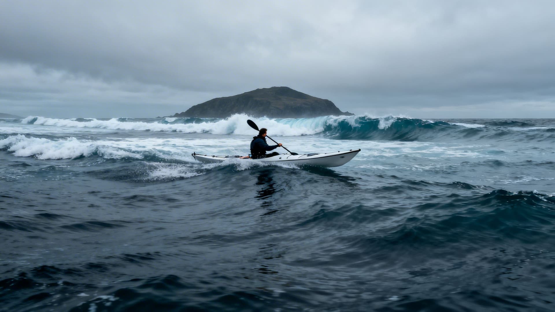 Atlantic groundswell building on an open west coast crossing, a sea kayak visible in the middle distance, white water breaking on a distant rock, sky and sea merging at the horizon