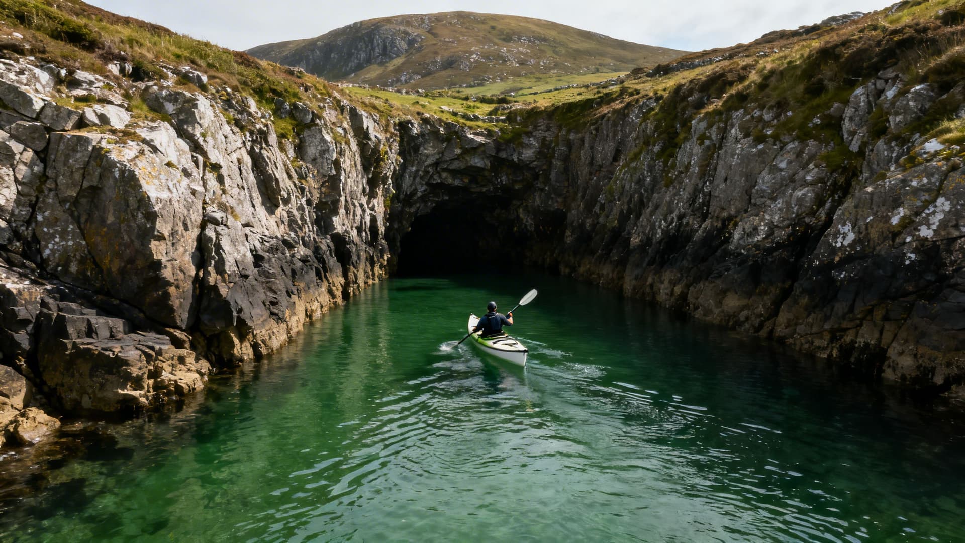 Sea kayaks on the shore at Ballinskelligs Bay with the Skellig rock silhouetted against the western sky, Kerry