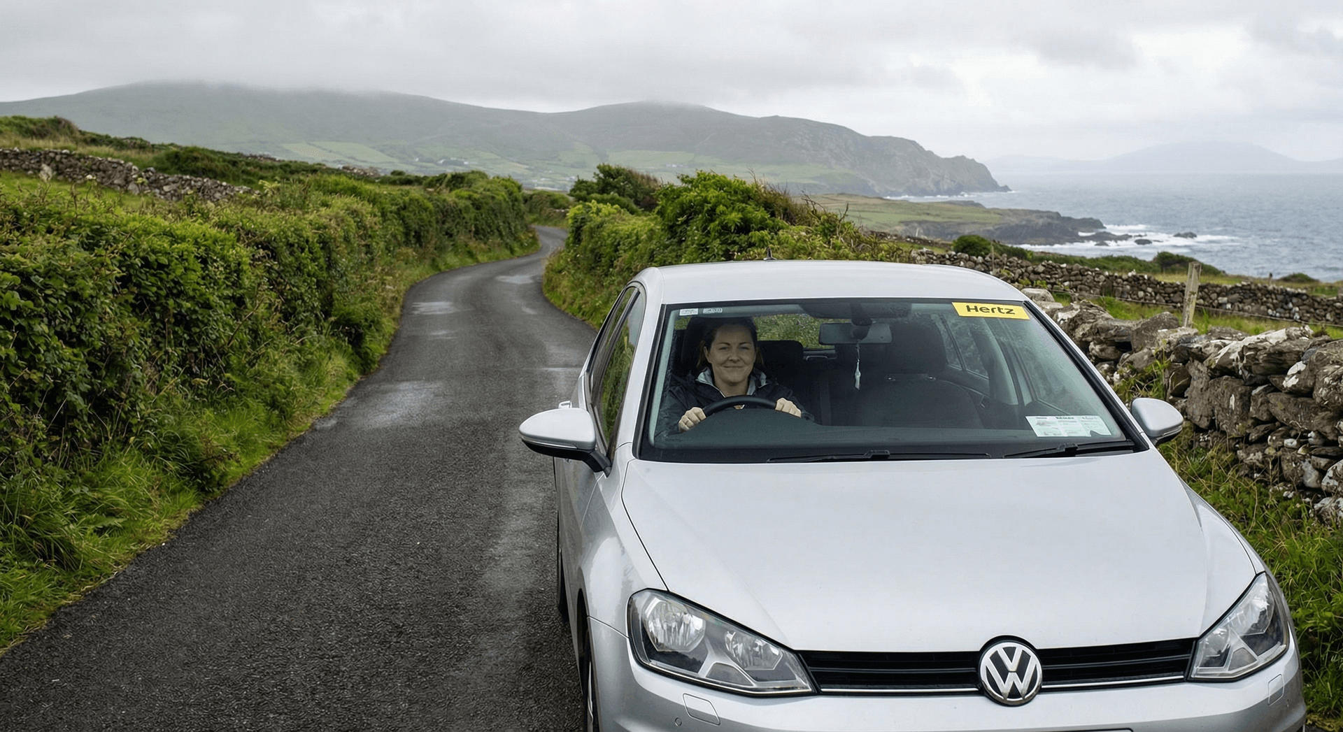 Woman driving rental car on narrow Irish country road