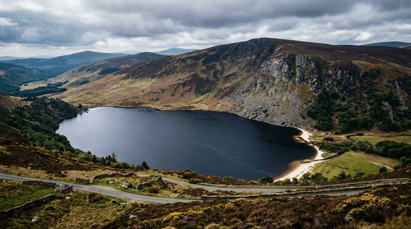 View of Lough Tay from the Military Road showing the dark water, white sand beach at the northern end, surrounded by mountains and heather-covered slopes